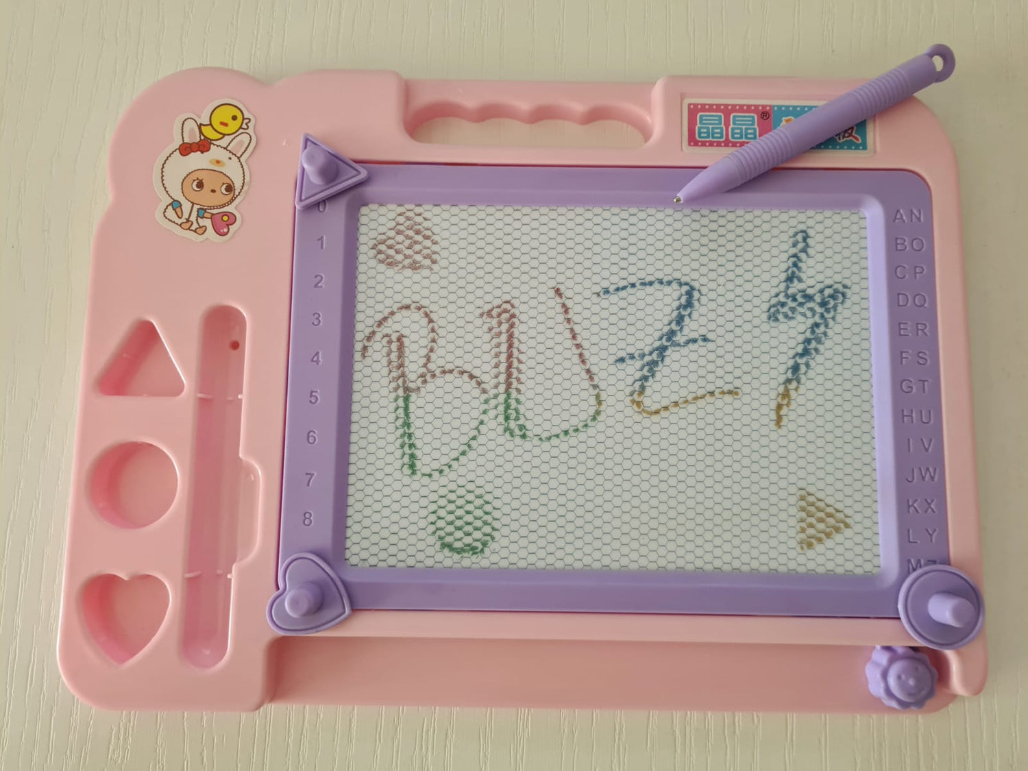 Tablita magnetica, cu stilou, 3 stampile magnetice diferite, cerc, triunghi si inimioara, bara ce sterge scrisul, dimensiune 27x20, culoare roz